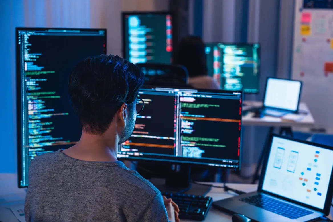 Picture of a developer devops team coding program with software computer at night in office.
